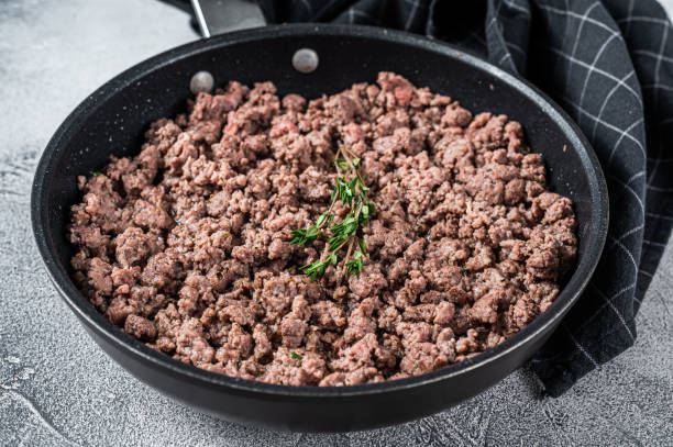 Fried mince beef and lamb meat in a pan with herbs. White background. Top view Fried mince beef and lamb meat in a pan with herbs. White background. Top view. cooked stock pictures, royalty-free photos & images