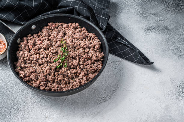 istock Fried ground mince beef and pork meat in a pan with herbs. White background. Top view. Copy space 1324782033