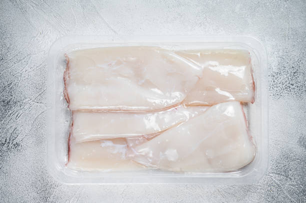 istock Fresh Raw Squid or Calamari in a vacuum package on a kitchen table. White background. Top view 1324782085