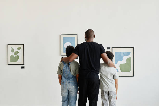 Family in Art Gallery Minimal back view at African-American family looking at paintings in modern art gallery, copy space museum stock pictures, royalty-free photos & images
