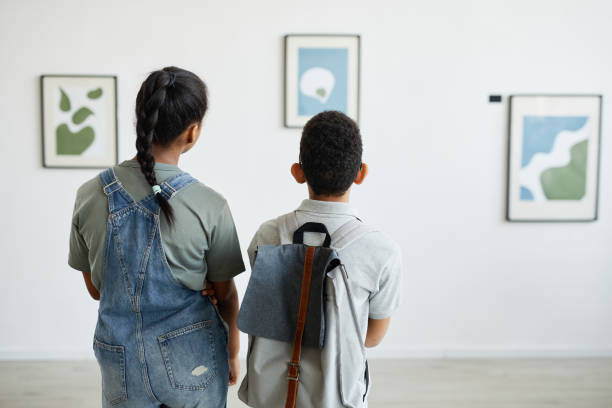 Schoolchildren in Art Museum Back view at two schoolchildren visiting art gallery and looking at modern abstract paintings, copy space 12 13 years photos stock pictures, royalty-free photos & images
