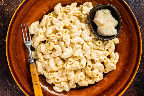 istock Macaroni Mac and cheese with Cheddar sauce in a plate. Dark background. Top view 1324783028