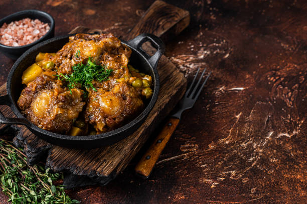 istock Beef oxtails stew with wine and vegetables in a pan. Dark background. Top view. Copy space 1324783846