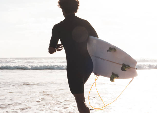 istock Unrecognizable surfer at the beach shore running to the waves 1324783890