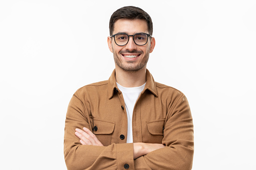 Young handsome smiling man in brown shirt and glasses, feeling confident, isolated on gray background