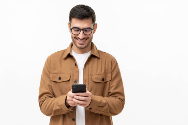 istock Young man looking at phone, standing isolated on gray background 1324786383