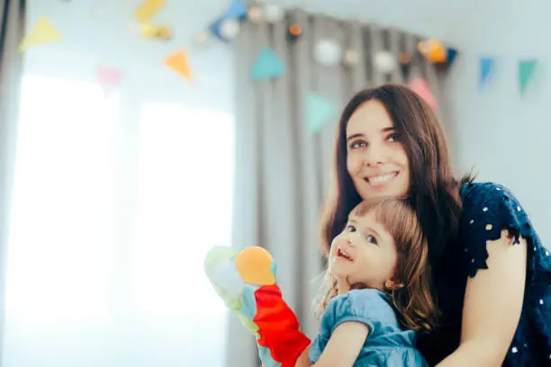 Photo of Mom Holding Little Toddler Girl Playing with Hand Puppet