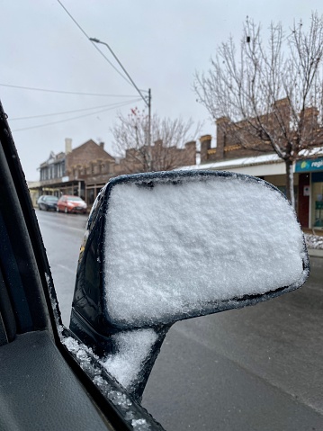 Freshly fallen snow completely covers this side mirror on a car in the street in Guyra, New England High Country, NSW