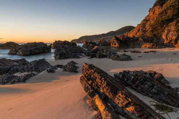 istock Sunrise seascape and a rocky beach softly lit by sunlight 1324798472