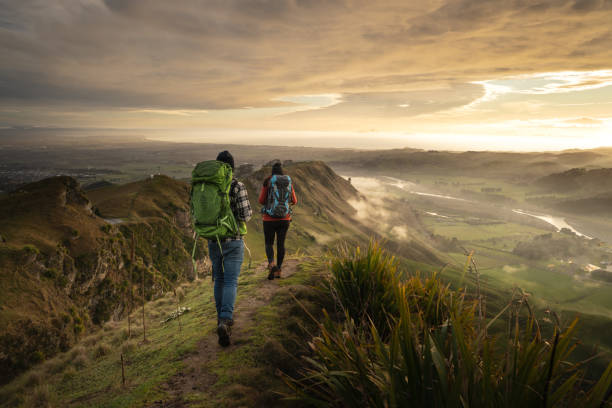 Backpackers walking on a mountain at sunrise. Travel concept stock photo