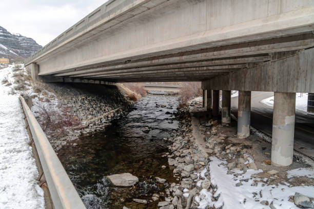 istock Rocky stream with shallow water and two lane road under an overpass highway 1324803714