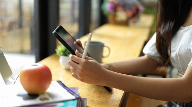 istock Side view of female student hands using digital tablet onthe bar with school elements 1324806144