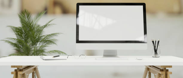 istock Desktop computer with mock-up screen on white desk in simple office room, 3D render 1324806168