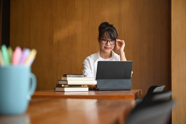 istock Young woman wearing glasses and using computer table in the library. 1324814256