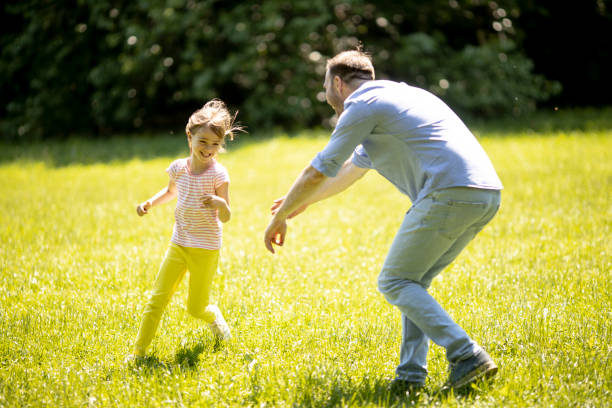istock Father chasing his little daughter while playing in the park 1324814415