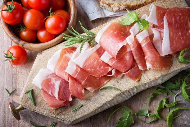 jamón crudo con tomates de céreda sobre tabla de cortar de madera, vista superior. - jamón de parma fotografías e imágenes de stock