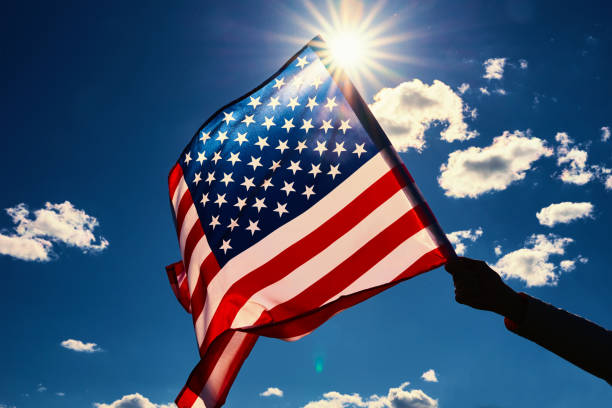 Waving usa flag in hand against blue sky