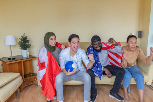entuzjastyczne multi-ethnic friends wspierają national soccer teams kanada i usa z domu. - sitting 20s adult american football zdjęcia i obrazy z banku zdjęć
