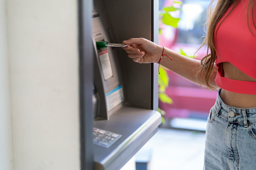 a young woman using an ATM on a city street