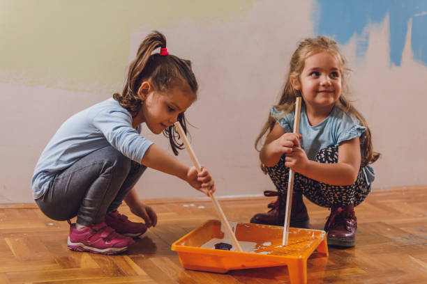 istock Two cute little girls mixing paint with sticks 1324824576