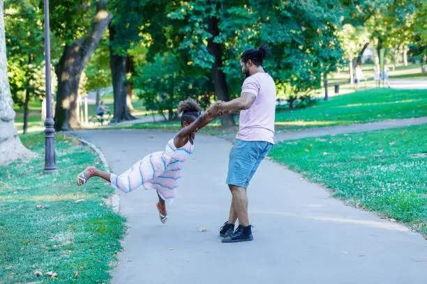 Photo of An African-American Man is Spending Lovely Moments with his Cute Daughter in Public Park.