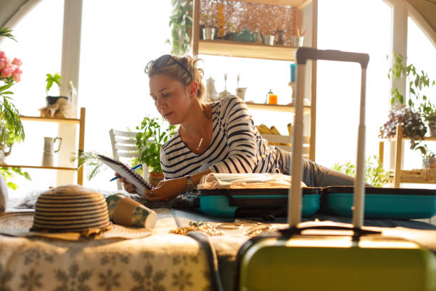 istock Woman checking her list while packing for a vacation 1324826921
