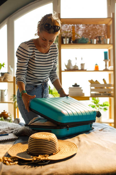 istock Woman closing a suitcase after she finished packing 1324826985