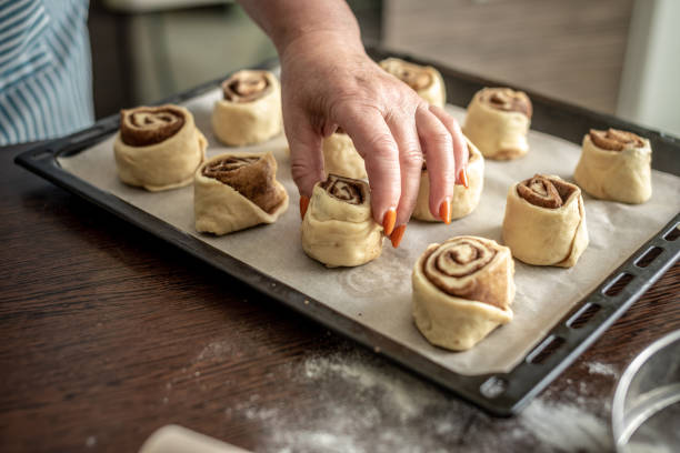 istock Women's hands are gently putting the raw cinnamon buns on a baking sheet before baking. Concept of the cooking process of homemade baking 1324829657