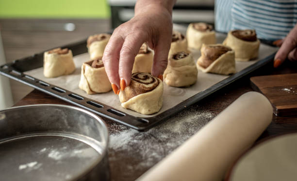 istock Women's hands are gently putting the raw cinnamon buns on a baking sheet before baking. Concept of the cooking process of homemade baking 1324829661