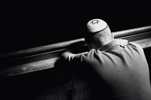 istock Young Jewish man wearing skull cap praying inside synagogue 1324830964
