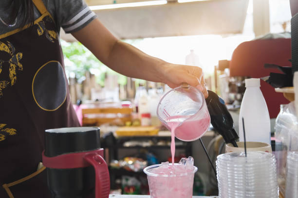 istock A female employee is pouring pink milk into a plastic cup for customers 1324833043