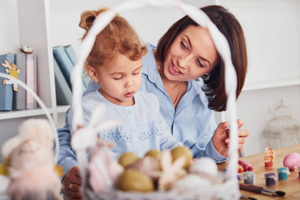 istock Mother with daughter celebrating Easter holidays together. Paints eggs 1324833141