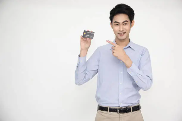 Young Asian man smiling, showing, presenting credit card for making payment or paying online business, Pay a merchant or as a cash advance for goods, Cardholder or A person who owns a card