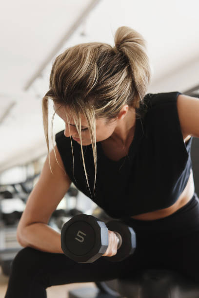 istock Athletic woman doing bicep curl exercise with a dumbbells in the gym 1324834621