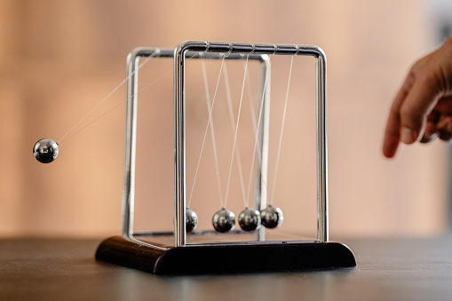 Concept For Domino Effect And Chain Reaction In Business With Newton's Cradle