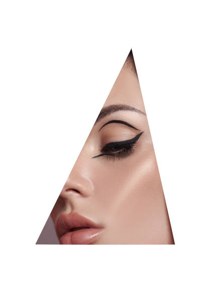 istock Beauty makeup women, eye brows eyelashes and lips in a triangular hole paper white background. Professional beauty makeup, place for text, copy space 1324840004