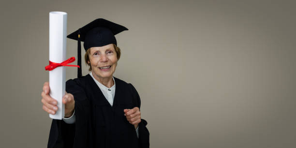 educación superior - mujer graduada madura en vestido de graduación y gorra que muestra el diploma. espacio de copia - old master fotografías e imágenes de stock