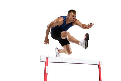 Caucasian professional male athlete jumping over the barrier isolated on white background. Running with obstacles concept. Muscular man. Action, motion, healthy, sport and lifestyle. Copyspace for ad.