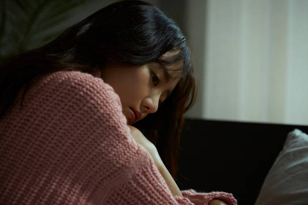 若いアジアの女性がベッドでリラックスしています - 暗い ストックフォトと画像