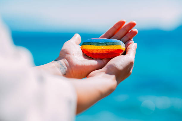 Woman Holding Pebble Painted in Rainbow Colors