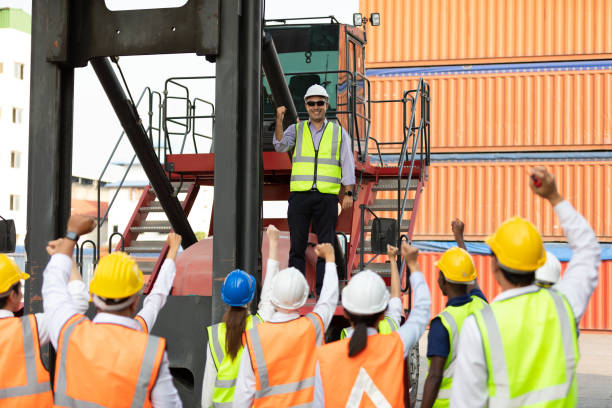 istock warehouse boss engineer standing on crane car with factory workers raise hand for congratulations in containers warehouse storage 1324843735