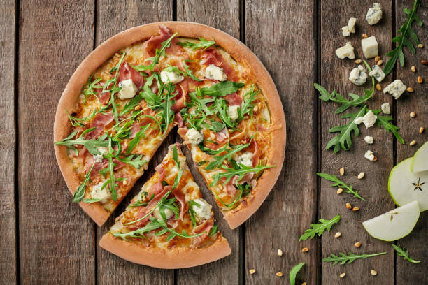 istock Sliced pizza with prosciutto, gorgonzola, pear, pine nuts, arugula 1324845395