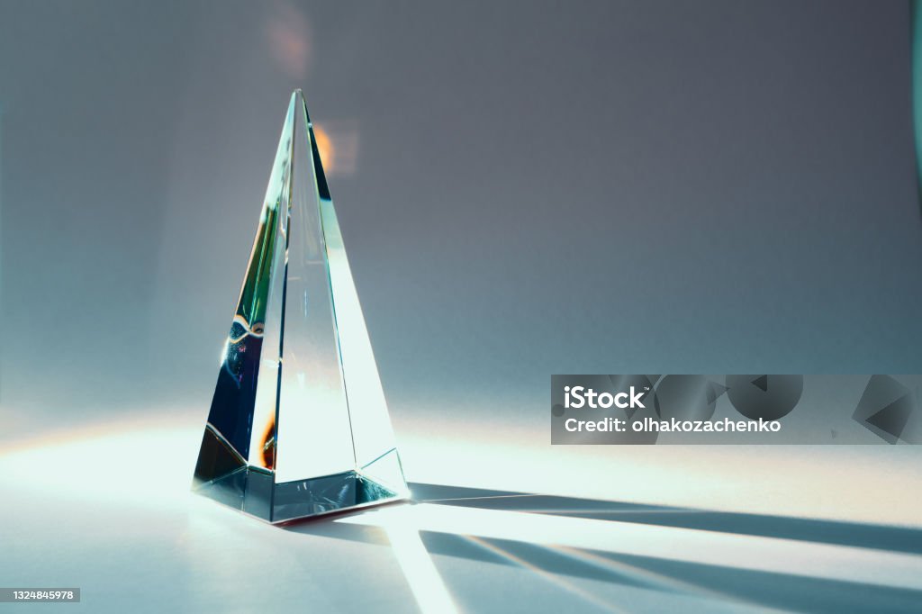 Glass pyramid prism with colorful sunlight reflection on background with copy space Glass pyramid prism with colorful sunlight reflection on background with copy space, horizontal Prism Stock Photo