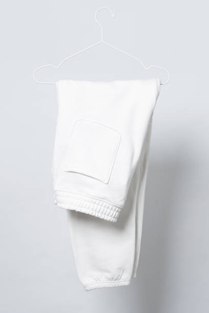 istock Blank white sweatpants hanging on a hanger against gray background 1324846923