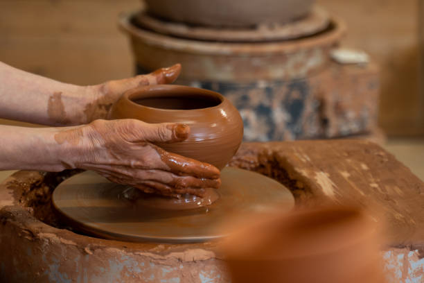 istock Hands of an elderly potter working with clay on a potter's wheel 1324847040