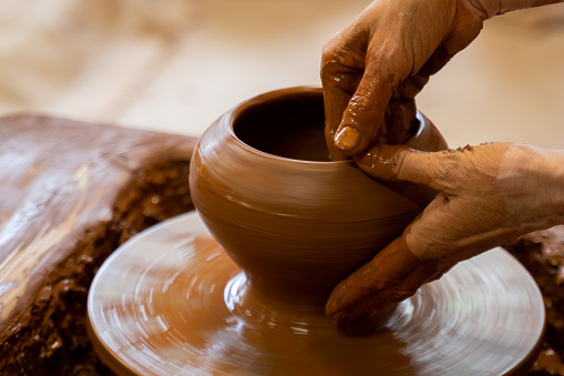 Elderly hands of a potter, creating an earthen jar on the circle. Old woman makes hand made ceramics from clay