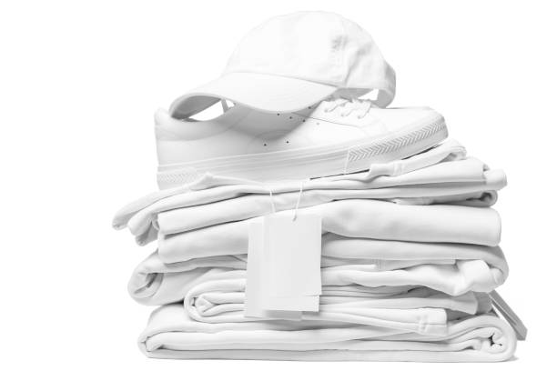 istock Stack of white clothes, trainers and baseball cap with a blank garment tag on white background 1324847413