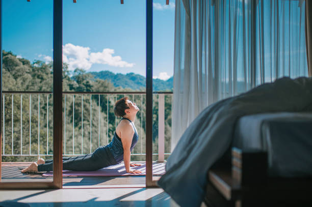 femme chinoise asiatique mi-adulte pratiquant le yoga pendant les vacances de séjour au balcon du patio le matin - curtain balcony bed sheet photos et images de collection
