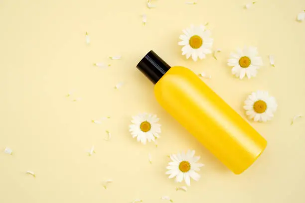 Photo of Bottle of Mockup cosmetic products with chamomile flowers on a yellow background