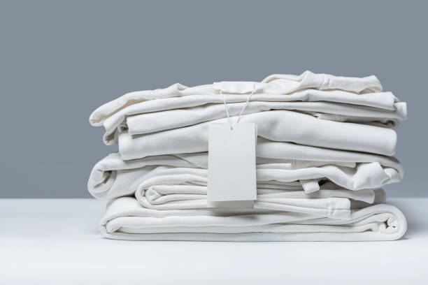 Stack of new white clothes with a blank garment tag